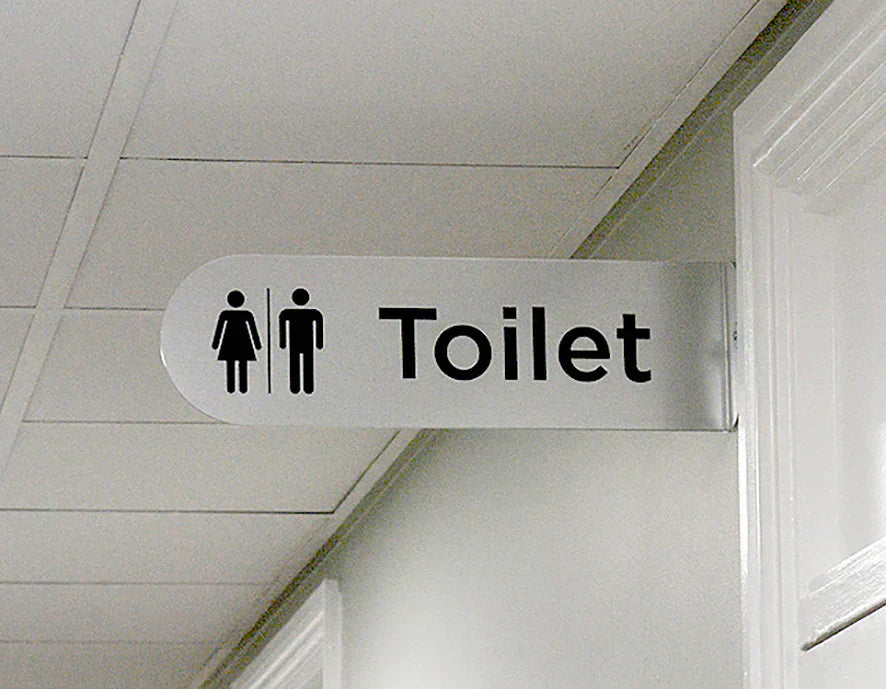 Projecting Toilet sign with male and female pictograms in a care home corridor.