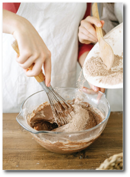 Dementia-friendly reminiscence image of chefs mixing a chocolate cake batter by hand and slowly adding ingredients. 