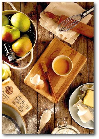 Dementia-friendly reminiscence artwork of a kitchen table covered in tools, ingredients and a recipe for making apple pie  